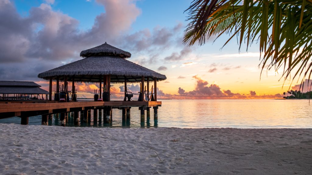 brown wooden cottage on beach during sunset